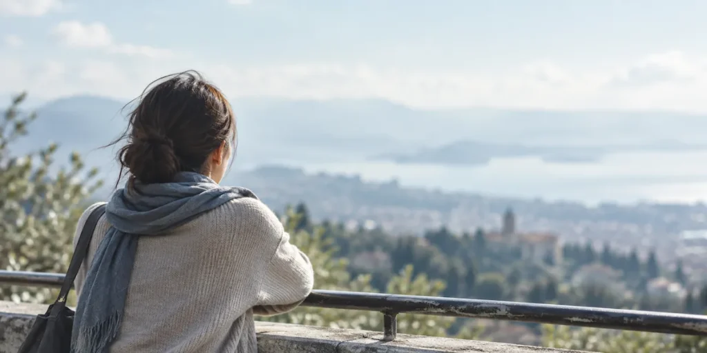 遠くの景色を見つめながら、ひとり静かに立つ女性の後ろ姿
