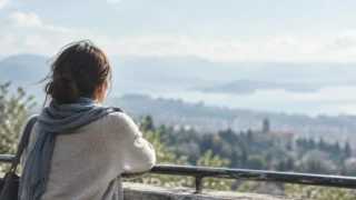 遠くの景色を見つめながら、ひとり静かに立つ女性の後ろ姿
